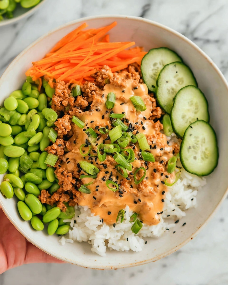 A white plate holds a colorful layered dish starting with a base of white rice on the left, topped with bright green edamame beans. Above that, there are thin orange carrot strips. On the right side of the plate, there are slices of fresh green cucumber sprinkled with black sesame seeds. At the center, a layer of browned ground meat is covered by a light orange creamy sauce, garnished with chopped green onions and more black sesame seeds. The plate sits on a white marbled surface, and a woman's hand is seen holding the plate from the bottom edge. photo taken with an iphone --ar 4:5 --v 7