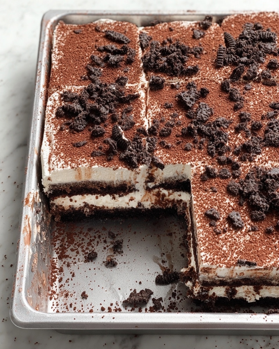 The image shows a rectangular dessert in a metal tray with one piece removed, revealing three layers: a bottom dark chocolate cake layer, a middle white creamy layer, and a top layer of dark chocolate cake covered with a thick white creamy layer. The top is dusted evenly with cocoa powder and sprinkled with crushed dark chocolate cookie pieces. The tray and dessert sit on a white marbled surface. Photo taken with an iphone --ar 4:5 --v 7