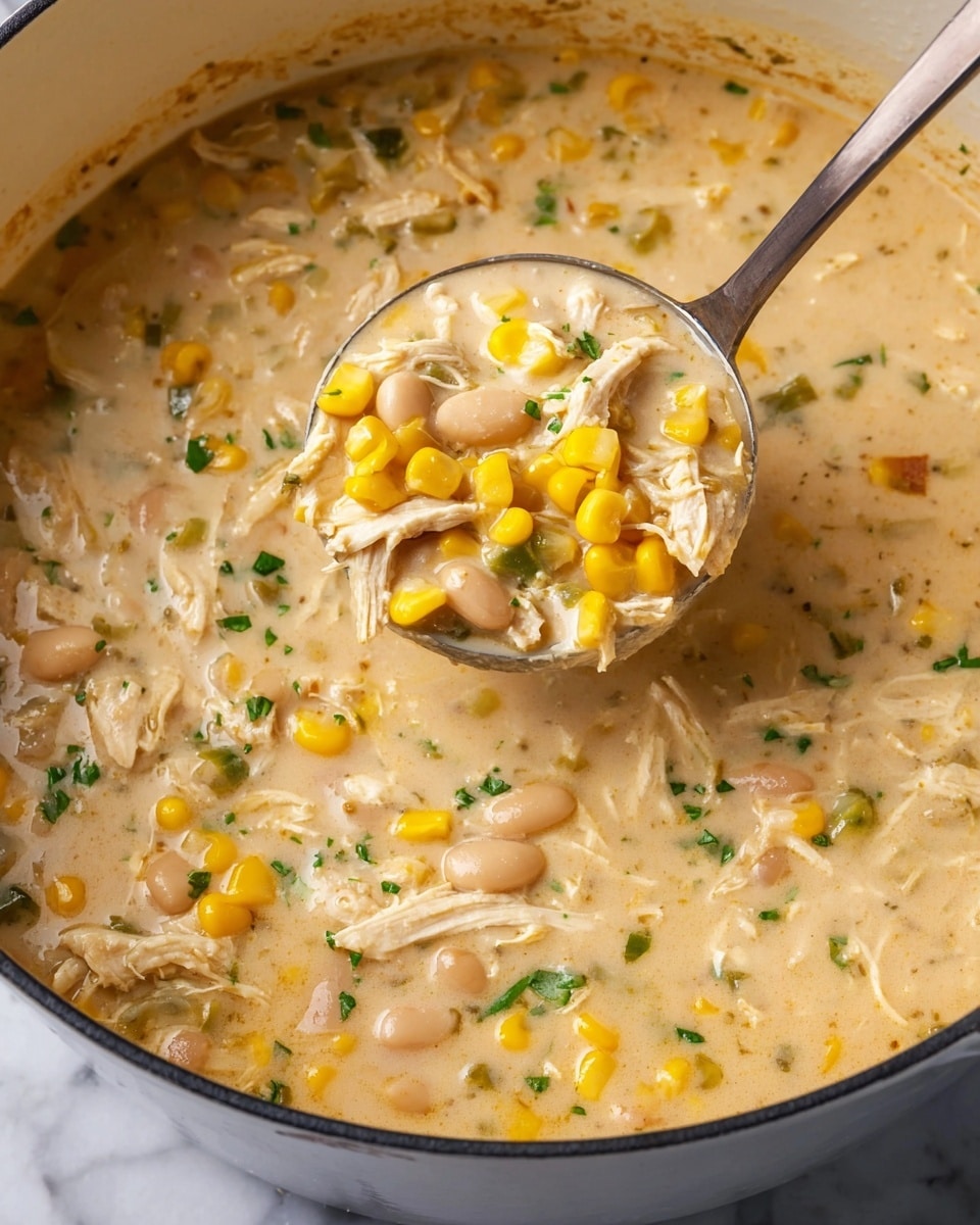 A close-up view of a creamy soup in a large white pot, showing a thick light beige broth filled with shredded white chicken, bright yellow corn kernels, white beans, small pieces of green herbs, and chunks of vegetables. The soup has a smooth, rich texture with visible bits of soft chicken and corn throughout. A metal ladle holds a scoop of the soup above the pot, clearly displaying the mixture of the creamy broth, colorful corn, and white chicken strands. The background is a white marbled texture. photo taken with an iphone --ar 4:5 --v 7