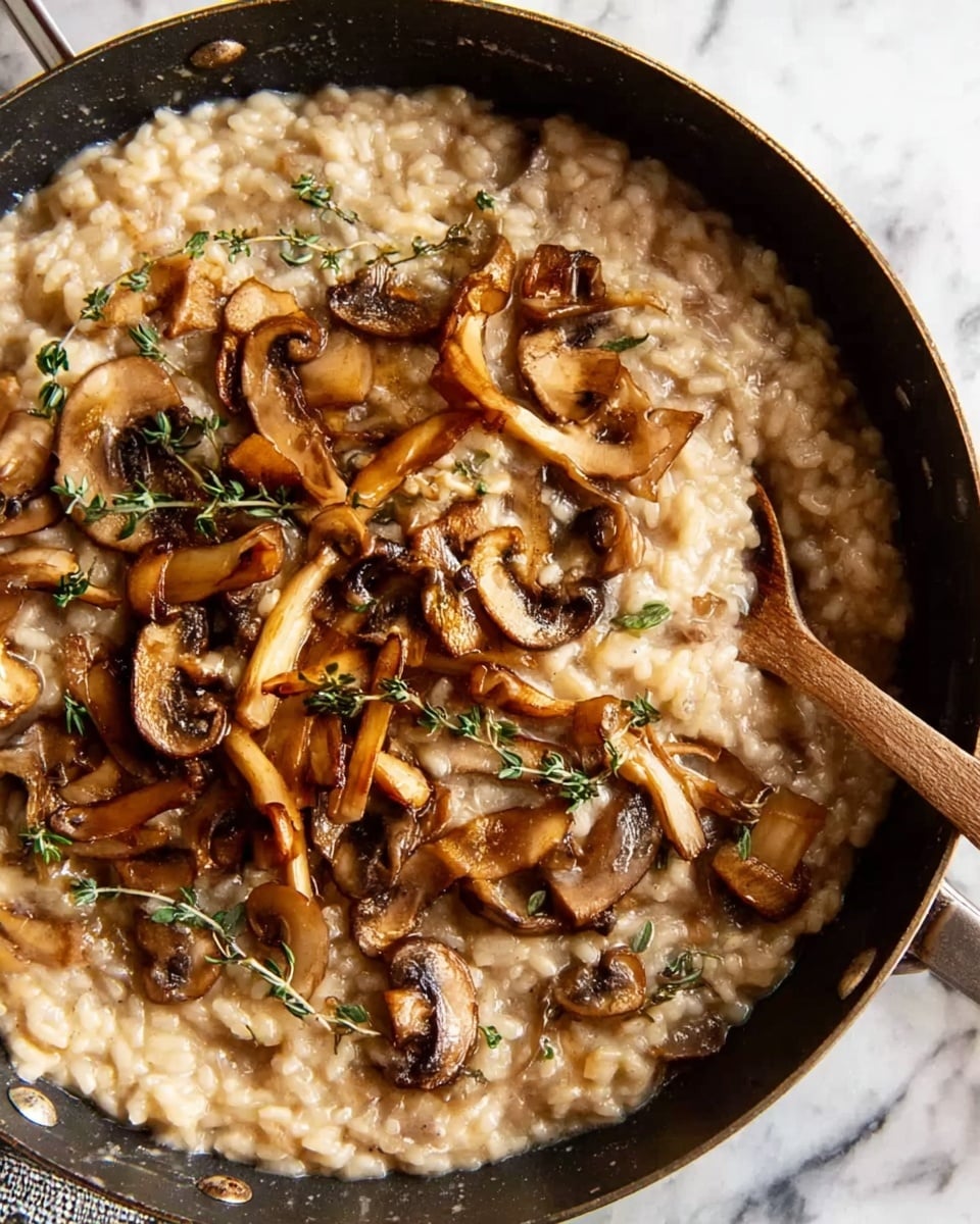 The image shows a close-up of a creamy mushroom risotto in a black pan placed on a white marbled surface. The risotto has a soft, beige color with a moist, creamy texture and is topped with several layers of cooked mushrooms in shades of brown and tan. The mushrooms are varied in shape and size, some thinly sliced, others in small clusters, scattered evenly over the risotto. Small green herb sprigs, likely thyme, are sprinkled on top, adding a touch of green contrasting with the warm earthy tones. A wooden spoon rests on the right side inside the pan, partly immersed in the risotto. Photo taken with an iphone --ar 4:5 --v 7