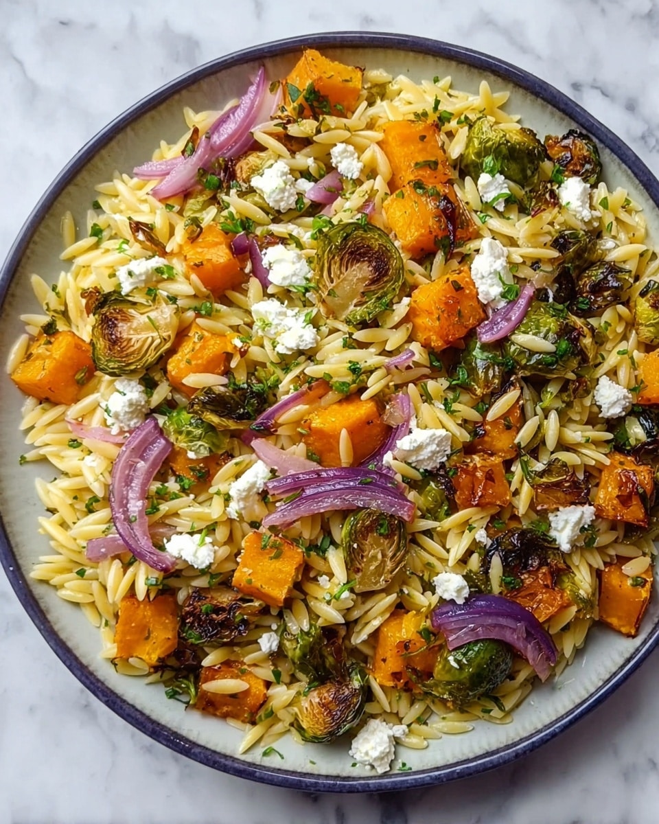The image shows a close-up of a bowl filled with a layered dish consisting of orzo pasta, roasted orange butternut squash chunks, green Brussels sprout pieces, and thin slices of purple-red onion mixed throughout. Small white crumbles of cheese are scattered on top, adding a creamy look. The orzo pasta is light cream-colored with a smooth texture, while the vegetables create a mix of bright orange, green, and purple colors with some charred edges. The bowl is white with a smooth surface, and it is placed on a white marbled textured surface. A wooden spoon is partially visible in the background. photo taken with an iphone --ar 4:5 --v 7