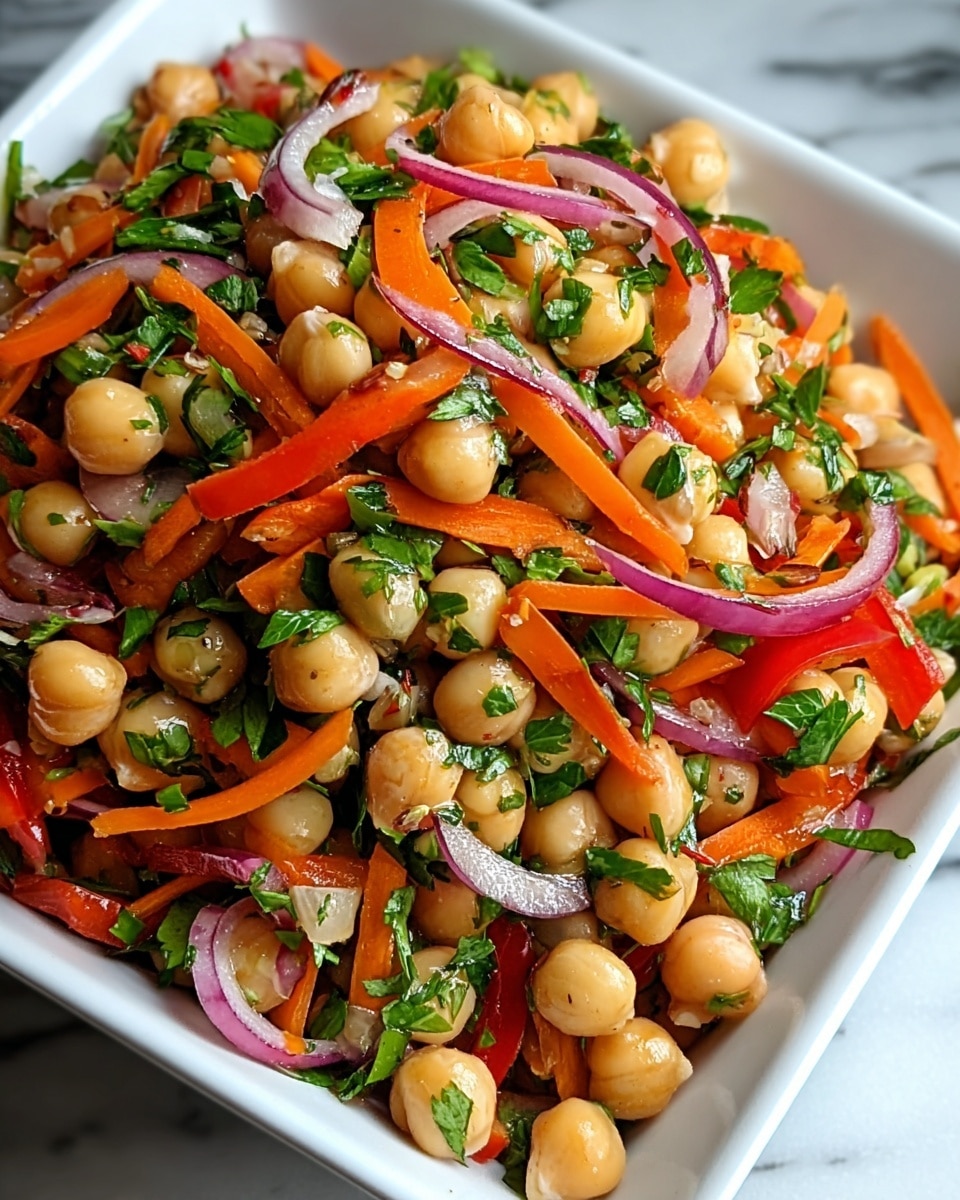 The image shows a close-up of a chickpea salad served in a white square dish, placed on a white marbled surface. The salad has one main layer filled with round, light beige chickpeas mixed evenly with thin strips of orange carrots, red bell peppers, and slices of purple onion. Fresh green parsley leaves are scattered throughout the salad, adding a touch of bright color and texture. The salad ingredients appear fresh and slightly glossy, giving a juicy and vibrant look. photo taken with an iphone --ar 4:5 --v 7