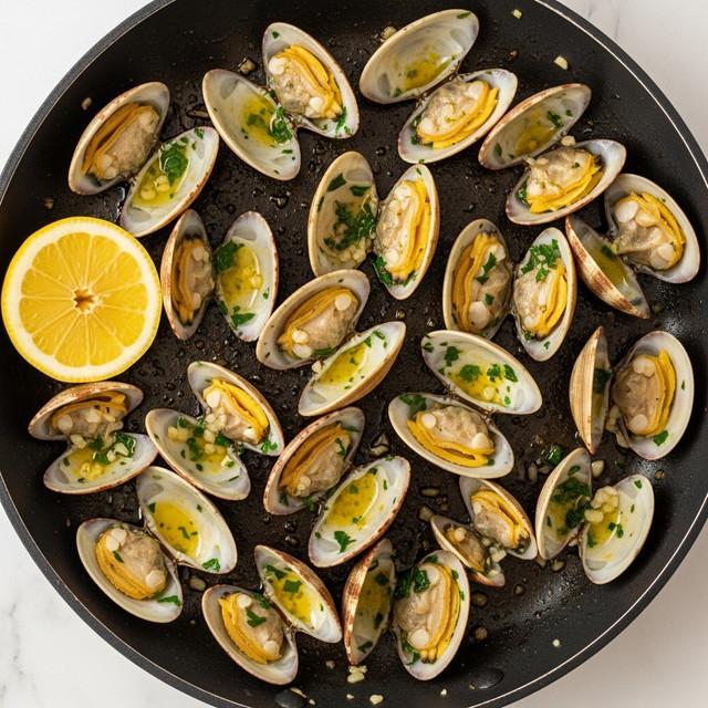 The image shows a close-up of cooked clams served in a black pan with their shells open, revealing the soft beige and yellow clam meat inside. The clams are covered with a glossy sauce that has bits of green chopped herbs, likely parsley, scattered all over. The shells are brown and purple with rough textures and some grill marks, and the sauce creates small pools of golden yellow liquid around the clams. The clams are piled closely together filling the pan, highlighting a fresh and juicy seafood dish. Photo taken with an iphone --ar 4:5 --v 7
