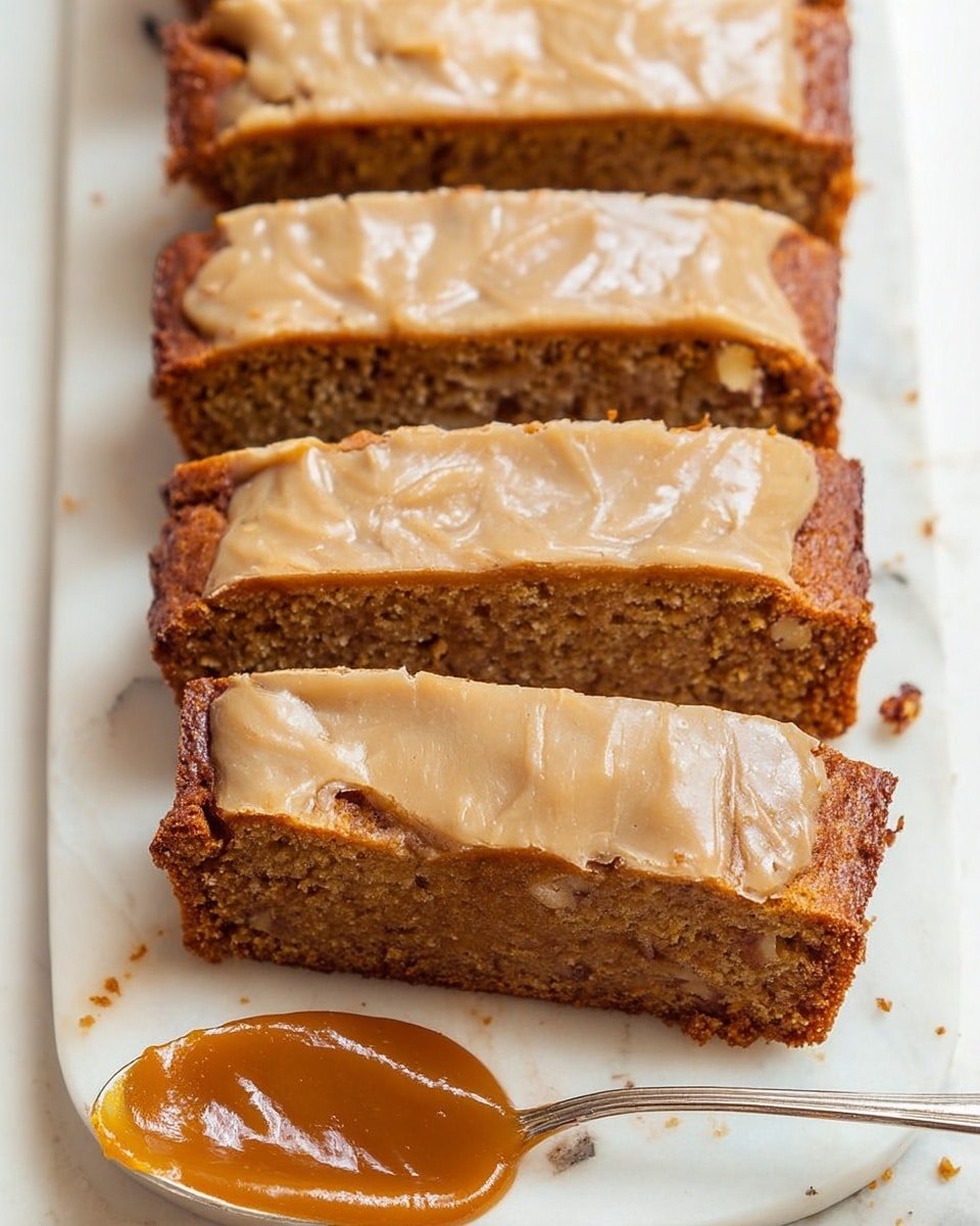 The image shows several rectangular slices of a moist brown cake with a light tan frosting on top. The cake has a dense texture with visible bits of nuts inside the middle brown layer. The frosting on top is smooth but has some cracks and a slightly glossy finish. The slices are placed neatly in a row on a white plate with a white marbled surface beneath it. In front of the cake slices, there is a spoon holding a thick caramel-colored sauce. photo taken with an iphone --ar 4:5 --v 7