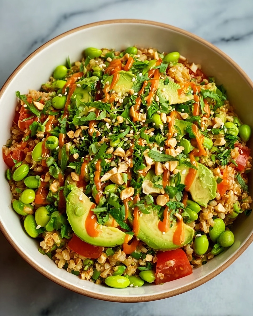 A round white bowl filled with a colorful grain salad made of light brown rice or bulgur mixed with bright green edamame beans, creamy avocado slices, and red tomatoes. The salad is topped with chopped fresh green herbs, chopped nuts, and small white sesame seeds. An orange sauce is drizzled over the top, adding contrast to the vibrant green and red ingredients. The bowl sits on a white marbled surface. photo taken with an iphone --ar 4:5 --v 7