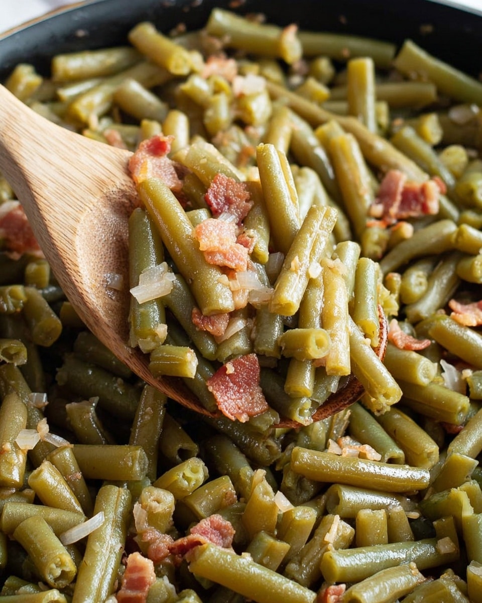 The image shows a close-up of cooked green beans mixed with small pieces of bacon and chopped onions, all stirred together in a pan. The green beans are cut into short, uniform sections, with a soft and slightly glossy texture. The bacon pieces are scattered throughout, adding a reddish-brown contrast, while the onions add a translucent white touch. A wooden spoon lifts a portion of the mix, highlighting the ingredients closely against the background filled with more green beans. The entire scene is set on a white marbled texture. photo taken with an iphone --ar 4:5 --v 7