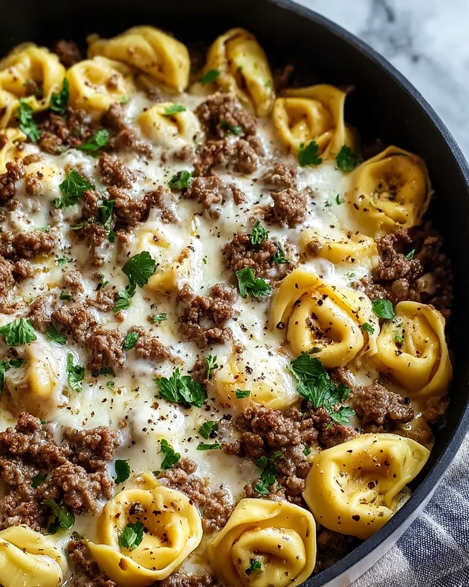 Close-up image of a cooked pasta dish in a black pan on a white marbled texture. The dish has three layers: the bottom layer is yellow tortellini pasta with a smooth, slightly shiny texture; the second layer is crumbled cooked ground beef, brown with a coarse texture, spread evenly on top of the pasta; the top layer is melted white cheese partially covering the beef and pasta, with some fresh green parsley leaves sprinkled on top, adding color contrast. The dish is garnished with black pepper flakes. photo taken with an iphone --ar 4:5 --v 7