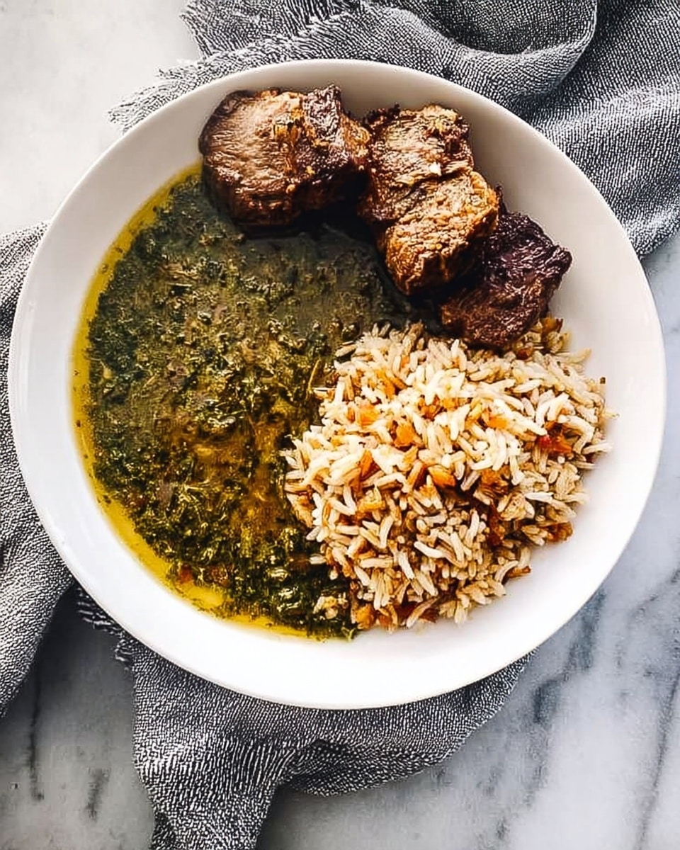 A white round plate on a white marbled surface holds three main layers: on the left side, a thick layer of dark green, finely chopped leafy stew with a slightly oily texture; on the top right, two pieces of browned, roasted meat with a textured surface; on the bottom right, a mound of cooked rice mixed with light brown toasted thin pasta, giving a mixed white and golden color. A soft gray cloth is partially visible under the plate on the top and right sides. Photo taken with an iphone --ar 4:5 --v 7