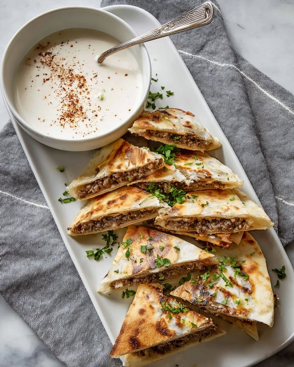 The image shows a white, rectangular plate with five triangular pieces of stuffed flatbread, each folded over a brown meat filling. The flatbread has a light golden color with grill marks and a slightly crispy texture. Fresh green herbs are scattered on top of the flatbread pieces, adding color contrast. At the top of the plate, there is a white bowl with a creamy white sauce sprinkled with a few dark red spices, and a silver spoon resting inside the bowl. The plate is placed on a soft gray cloth with white stripes, all set on a white marbled surface. photo taken with an iphone --ar 4:5 --v 7