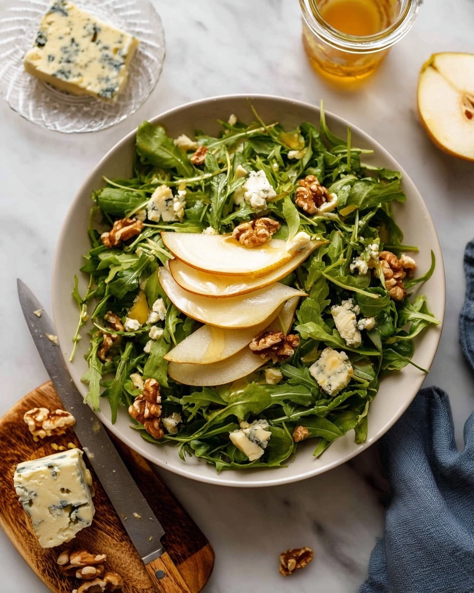 A white bowl filled with a salad made of bright green arugula leaves as the base layer, topped with thin slices of light yellow pear arranged unevenly, scattered chunks of white and blue-veined cheese, and several pieces of brown walnuts spread across the top. The bowl sits on a white marbled surface with a small jar of dressing behind it. Next to the bowl is a small clear glass dish holding a block of the same blue cheese, some pear slices, a woman's hand holding a knife with a wooden handle, and part of a cut pear. Photo taken with an iphone --ar 4:5 --v 7
