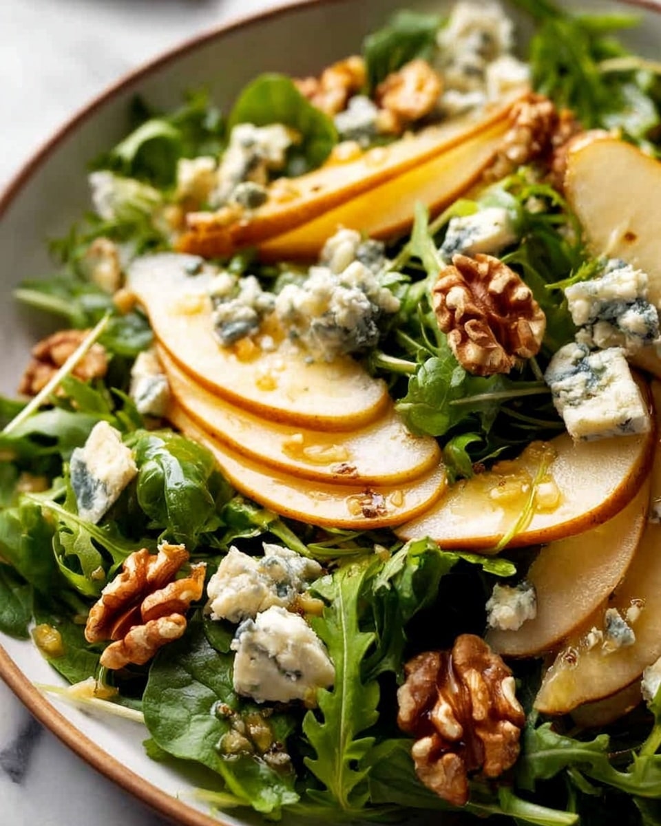 A close-up image of a fresh salad arranged in a white bowl on a white marbled surface. The salad shows a base layer of dark green arugula leaves, textured and leafy, spread evenly. On top, there are several thin slices of light yellow pear with a hint of brown on the edges, layered overlapping in the center. Scattered across are chunks of creamy blue cheese with blue mold spots, adding texture and color contrast. Bright brown walnuts are placed throughout, their rough, crinkled surfaces standing out against the greens and cheese. The overall look is fresh, crisp, and textured, with a natural and healthy vibe. Photo taken with an iphone --ar 4:5 --v 7